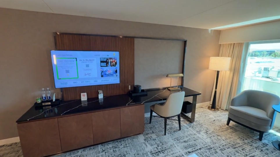 TV mounted on a stand next to a workdesk and chair.