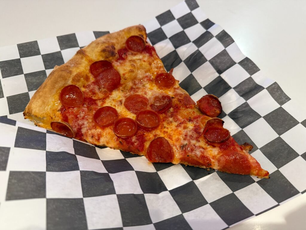 A slice of pepperoni pizza on a checkered napkin.