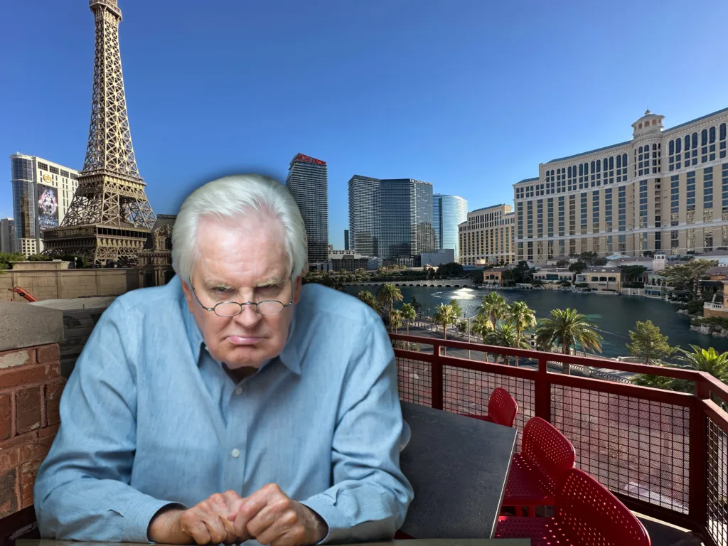 A very grumpy old man staring into the camera with Vegas resorts in the background.