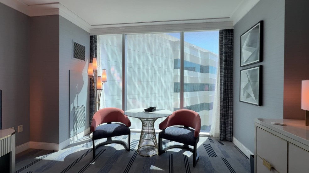 Two chairs and a table sit in front of the window in the room.