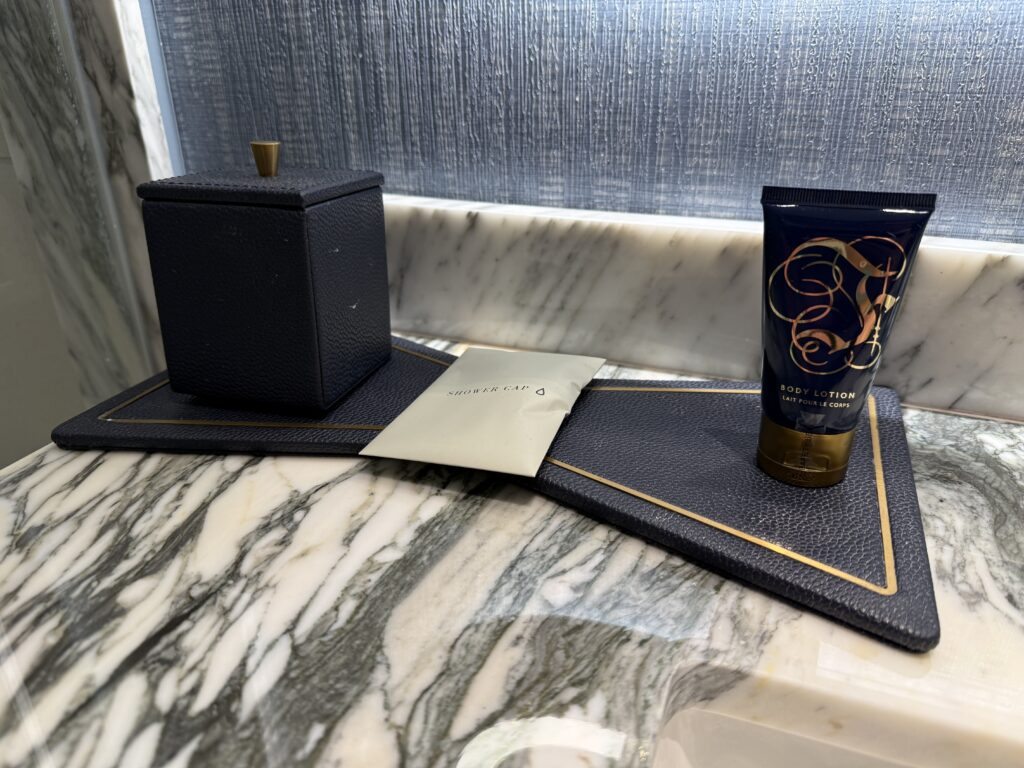 Complimenatery toiletries on a bowtie mat on the countertop. 