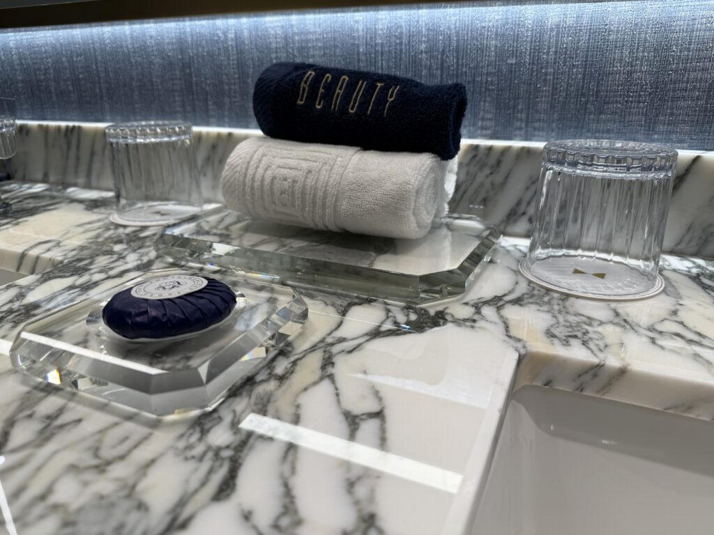 rolled towels on display between the two sinks flanked by upside down glasses. 