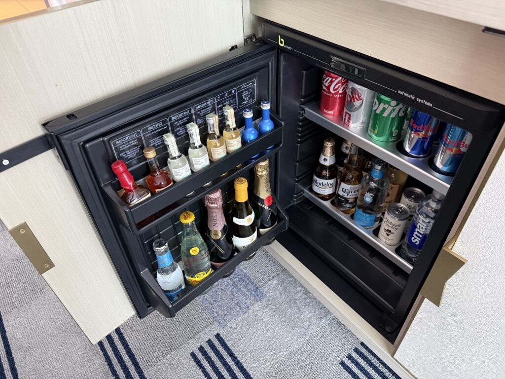 Refrigerated mini bar stocked with drinks. 