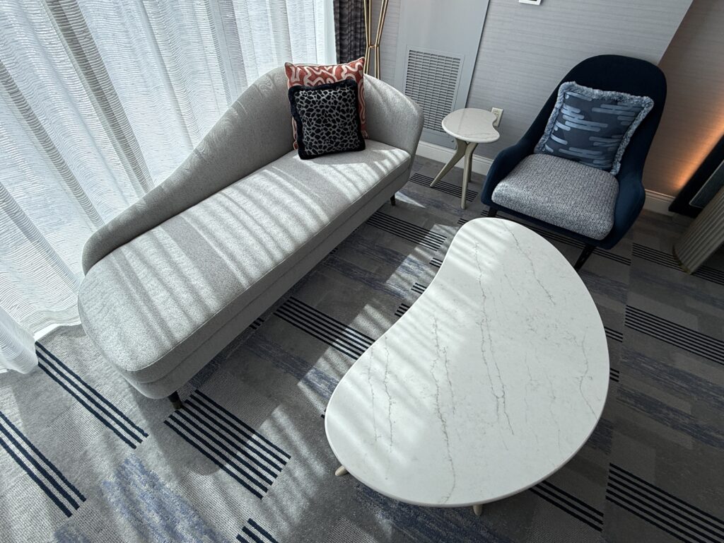A closer look a the small couch, table, and another chair in front of the windows. 