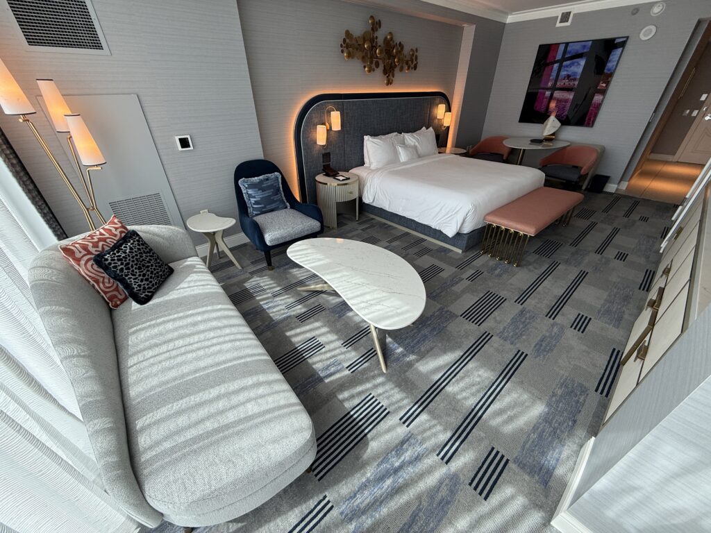 Antoher angle of the room that shows a chaiz lounger and table in front of the window and the king bed in the background. 