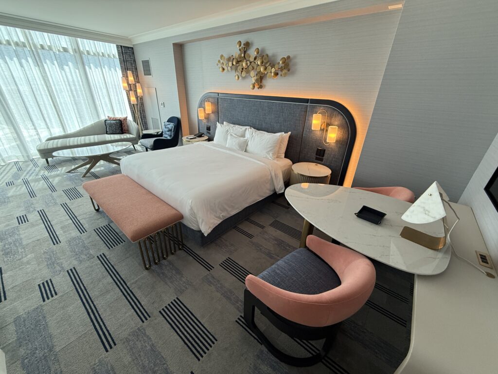 A wide angle of the room that shows the king bed and window in the background. 