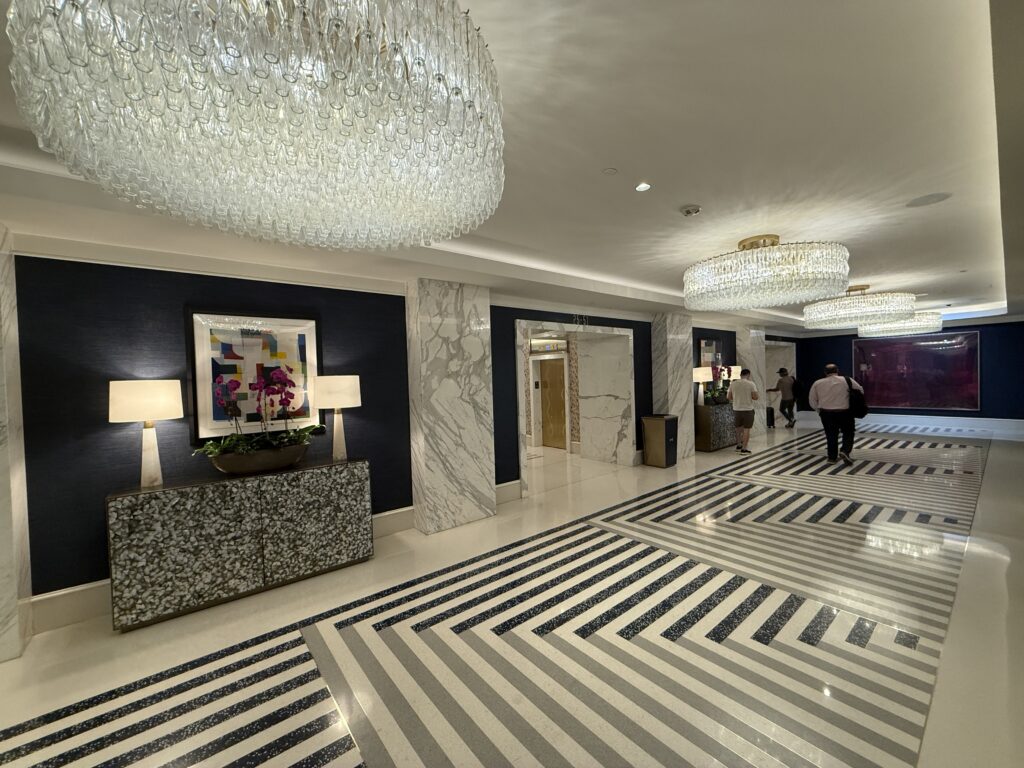 Inside the main level elevator lobby, which have decorative lighting, stone finishes, and a zig zag pattern on the floor. 
