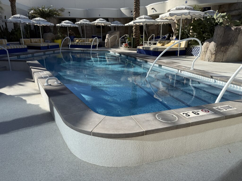 A small stand alone pool, surrounded by cabanas. 