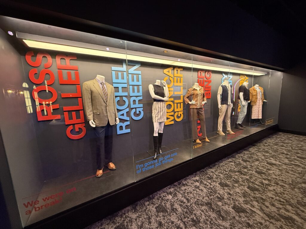 A row of costumes for each main character behind glass. 