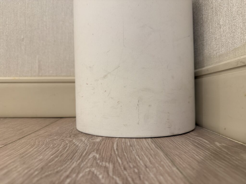 A dinged up white garbage can.