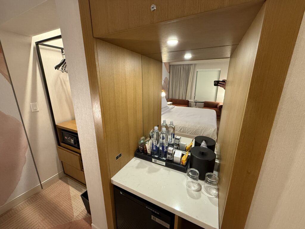 A dry minibar atop a counter with a mirror above it. 