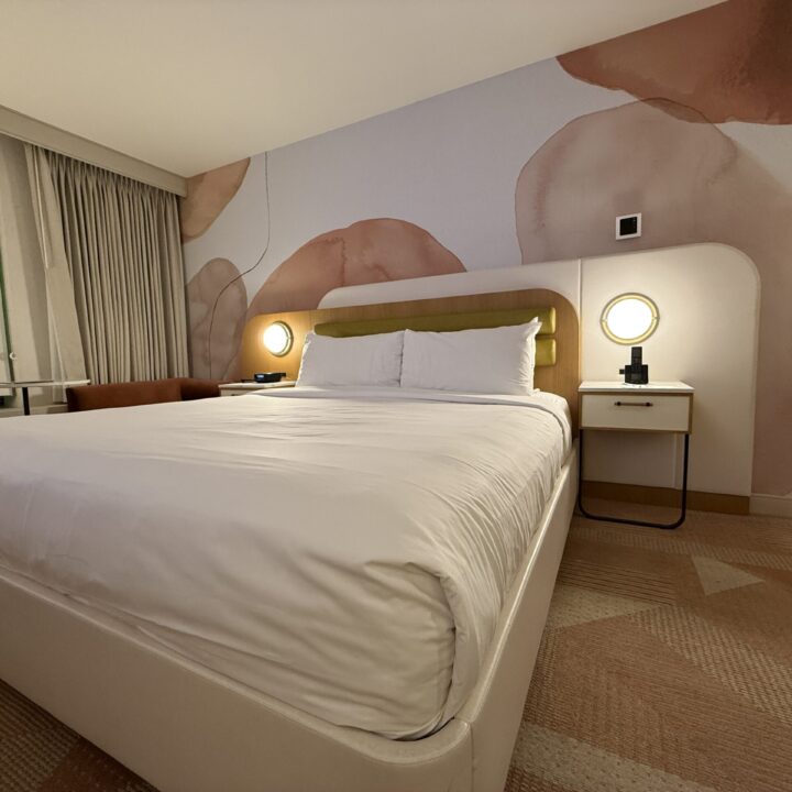 The king bed with the floral, pink accent wall behind it.