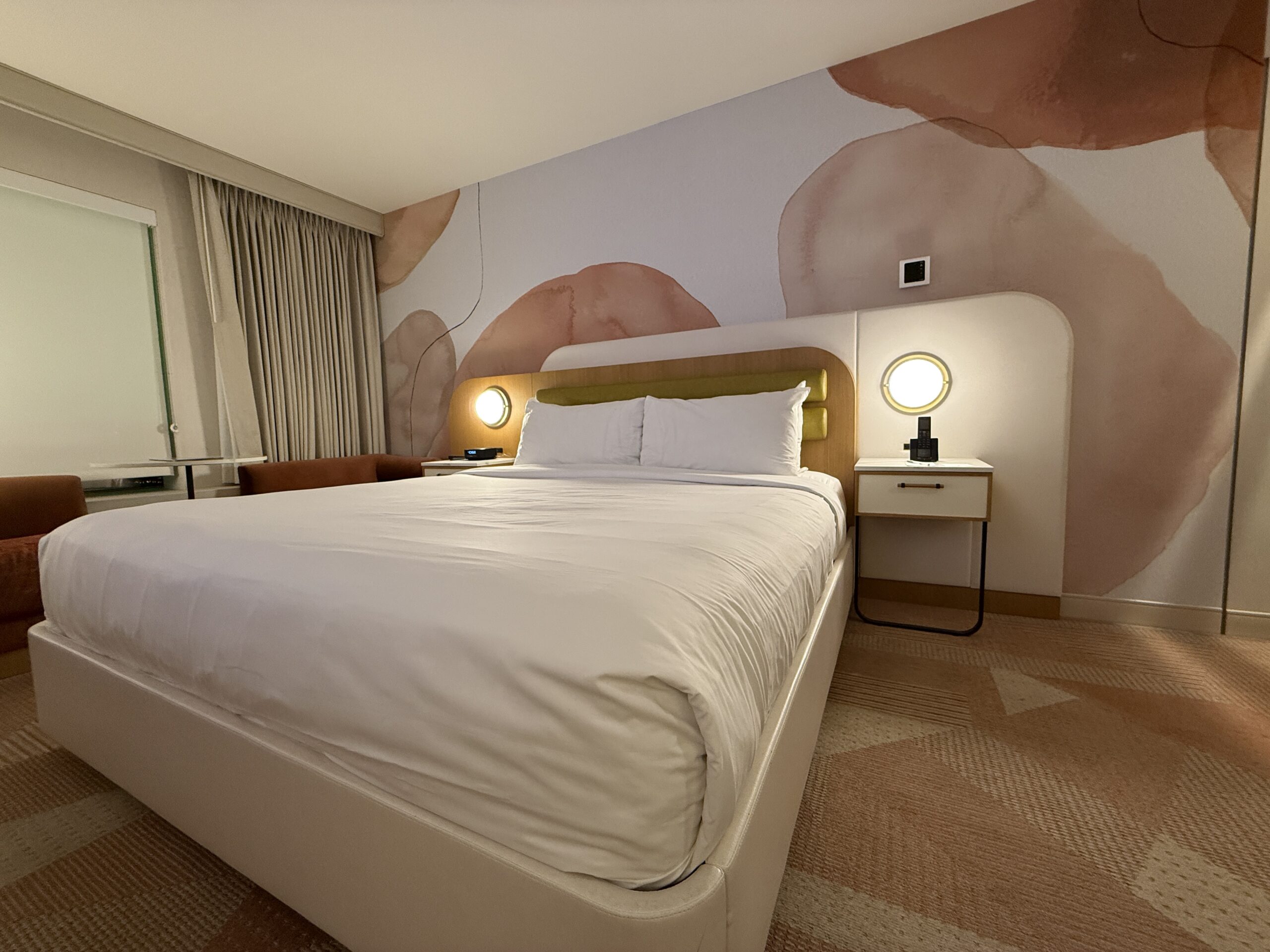 The king bed with the floral, pink accent wall behind it.