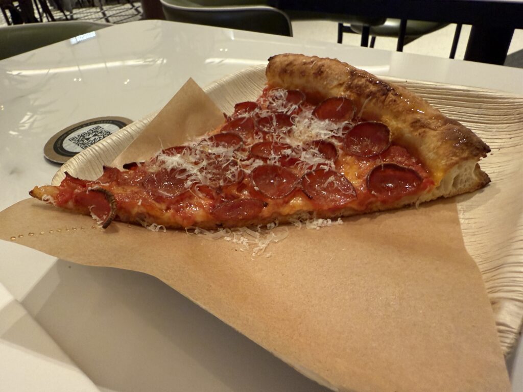A slice of pepperoni pizza from Miami Slice on a tray with grated parm atop it.