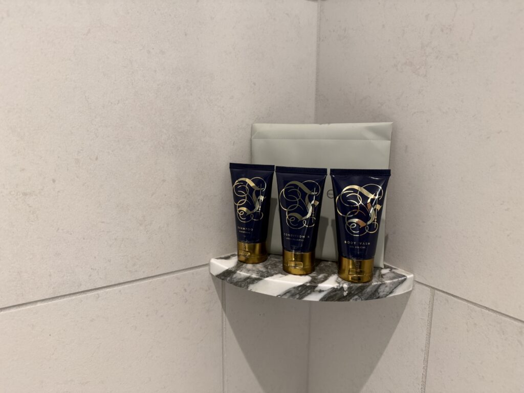 3 tubes of conditioner, shampoo, and body wash on a shelf in the bathroom. 