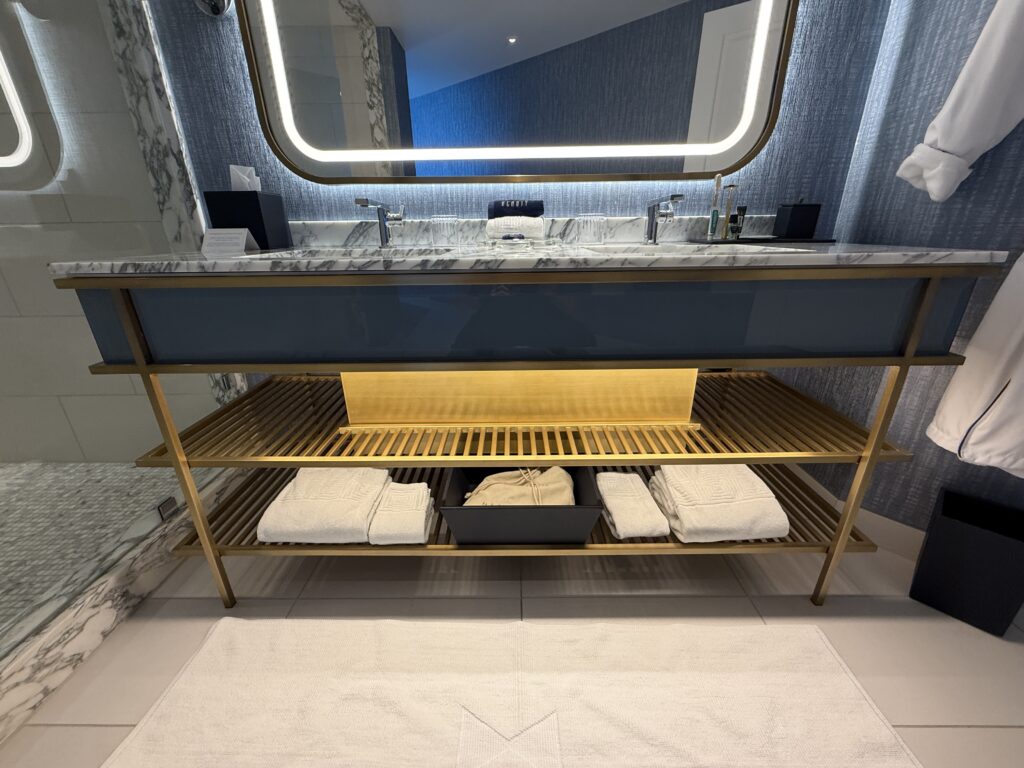 The bottom shelf of the vanity, which has folded towels and a nightlight illuminated. 