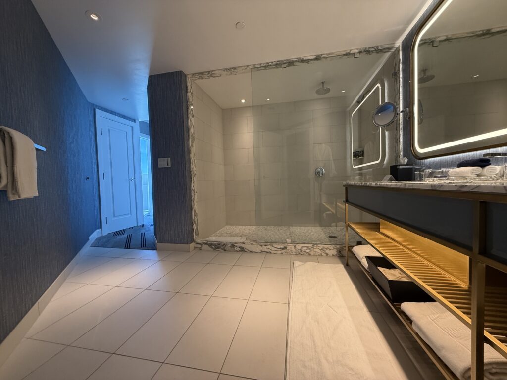 A long, glass-enclosed shower with the vanity varily visible to the right. 