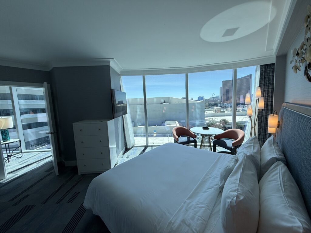 Another angle which shows the King bed pointed at the TV, the entryway door to the bedroom from the living area, and floor to ceiling windows in the background. 