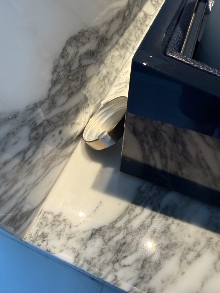 Small metal cap, garbage, on the countertop behind the minibar. 