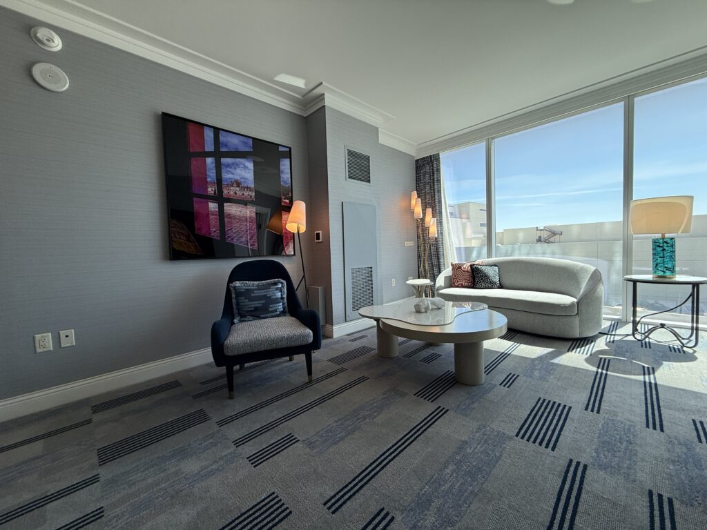 Furnishings in the living area, including a loveseat, table, and blue chair underneath wall art. 