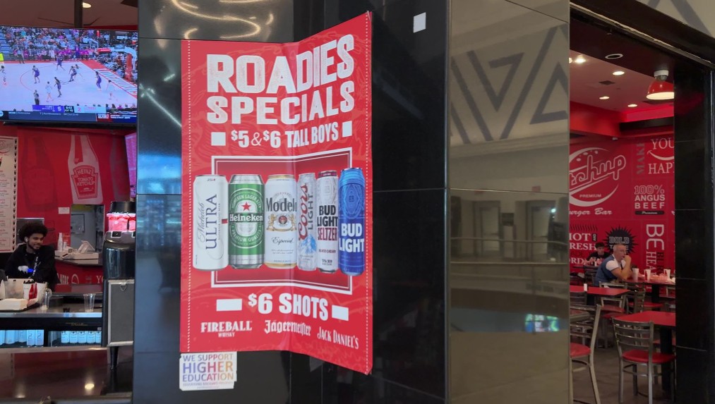 Red promotional poster titled 'ROADIES SPECIALS' advertising $5-$6 tall boys with displayed beer cans at Ketchup.