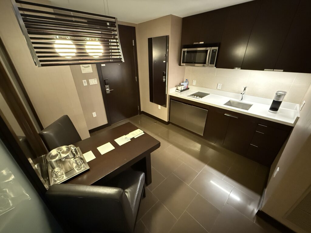 A kitchenette in the Studio Parlor, which has a table, stove, microwave, and sink. 