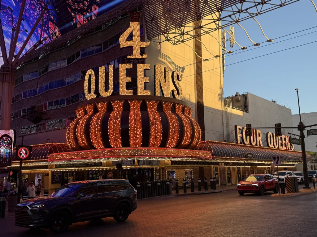 Exterior isignage of 4 Queens, illuminated at dusk with the North Tower visible.