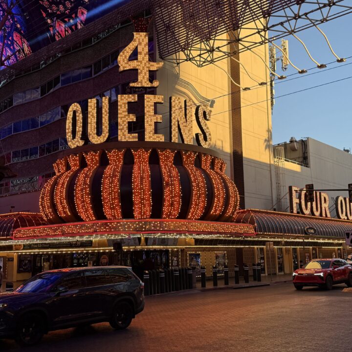Exterior isignage of 4 Queens, illuminated at dusk with the North Tower visible.