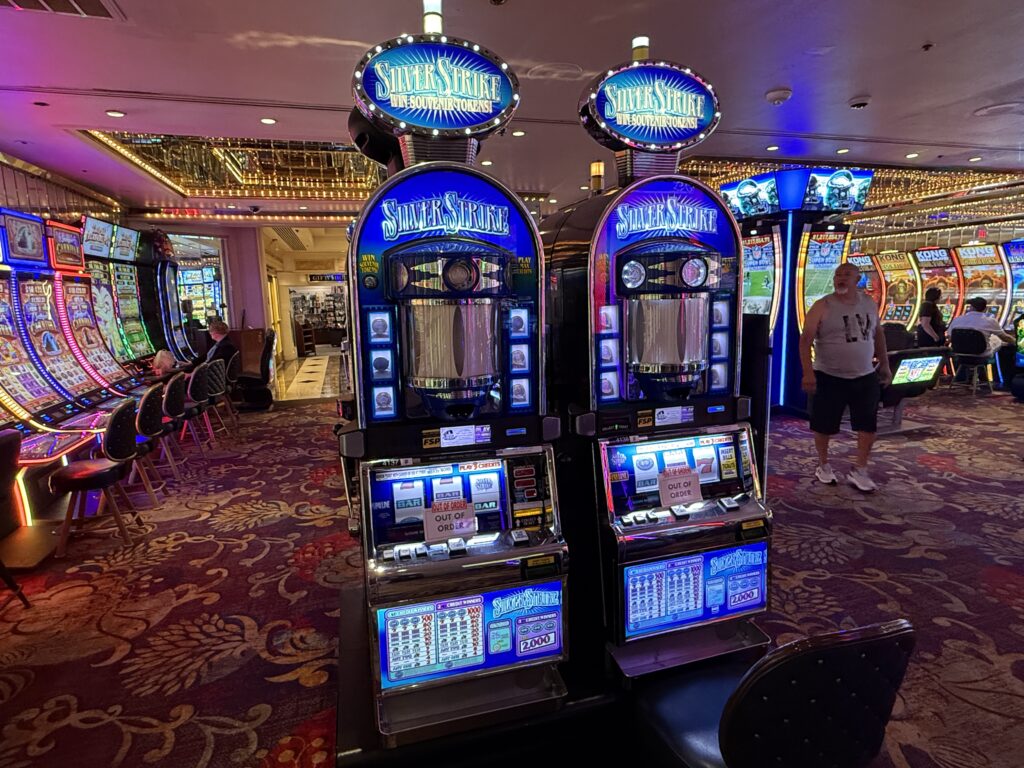 Row of Silver Strike slot machines with blue branding and neon lights in a casino surface area