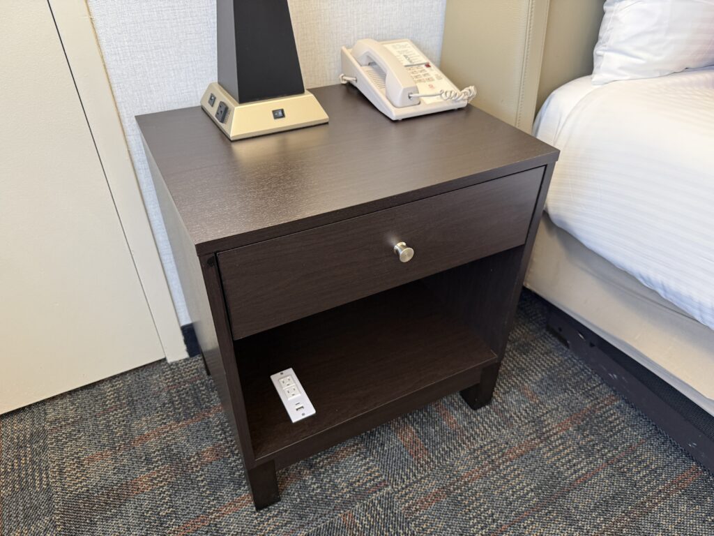 A dark wood besdie table with ample charging capability built in.