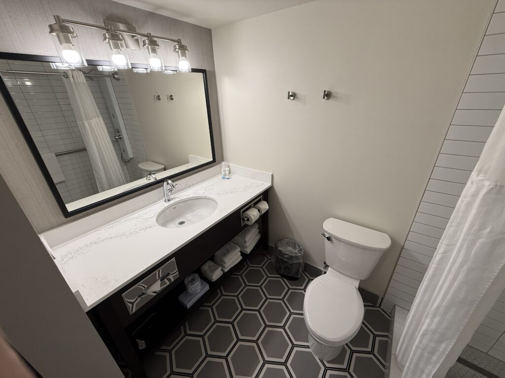 1 sink vanity, toilet, and a fashionable gray patterened floor.