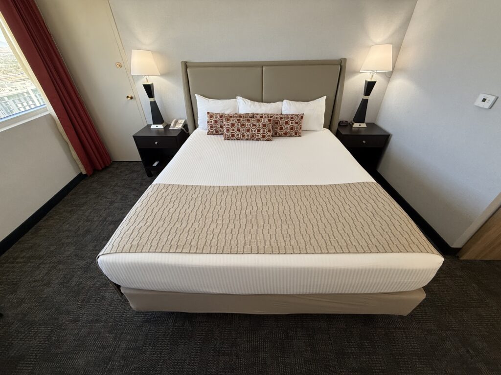 A head on shot of a king bed, flanked by end tables with lamps atop them.