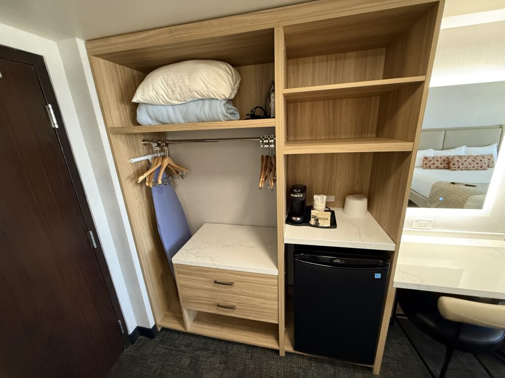 An open colet with an iron, ironing board, blankets and an extra pillow.