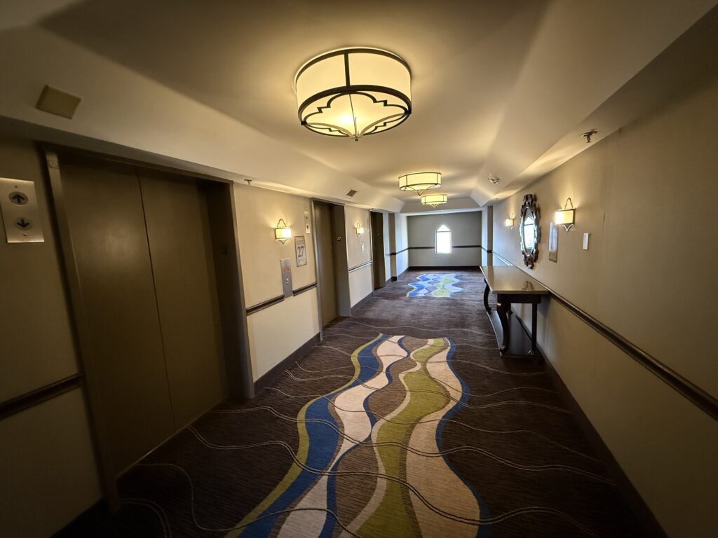 Hotel elevator lobby, with fresh carpeting, and warm lighting. 