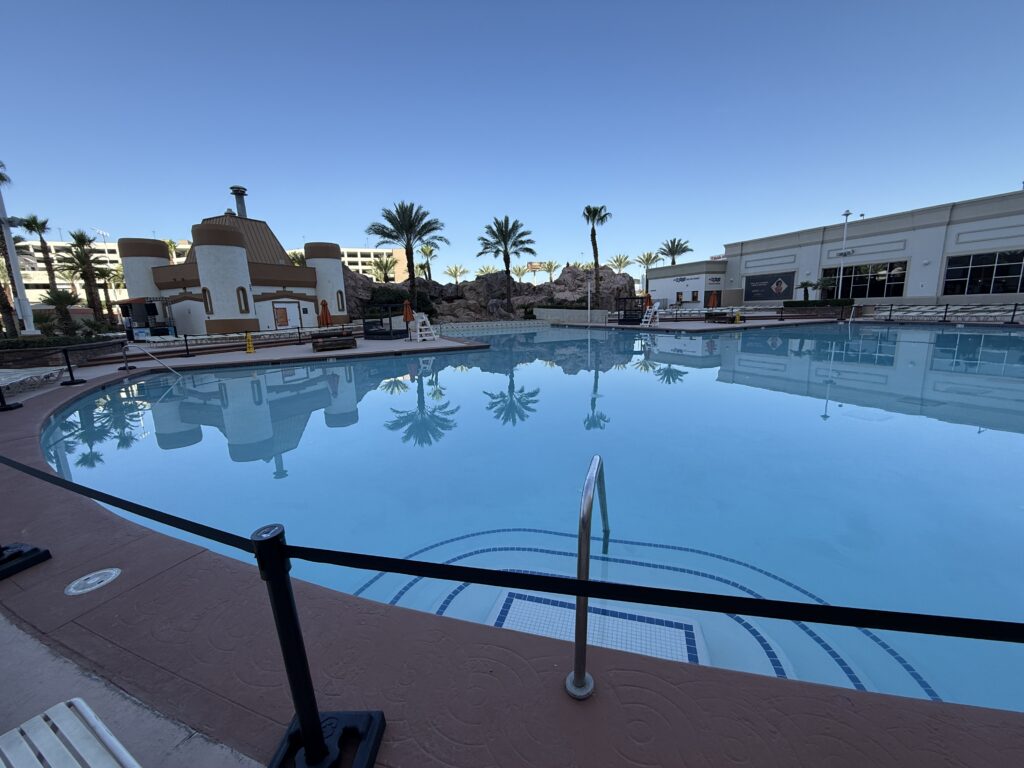 A shaded outdoor pool with palm trees in the distance. 