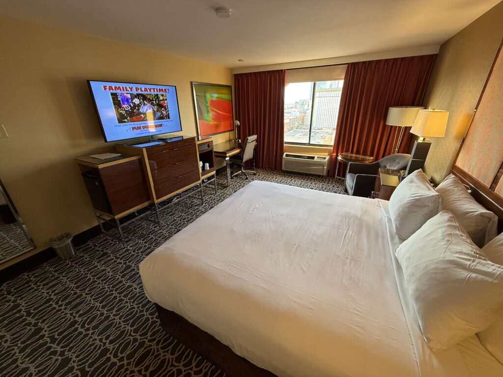 Another wide angle look at the king bed, pointed at the TV which is sitting atop a tv stand. 