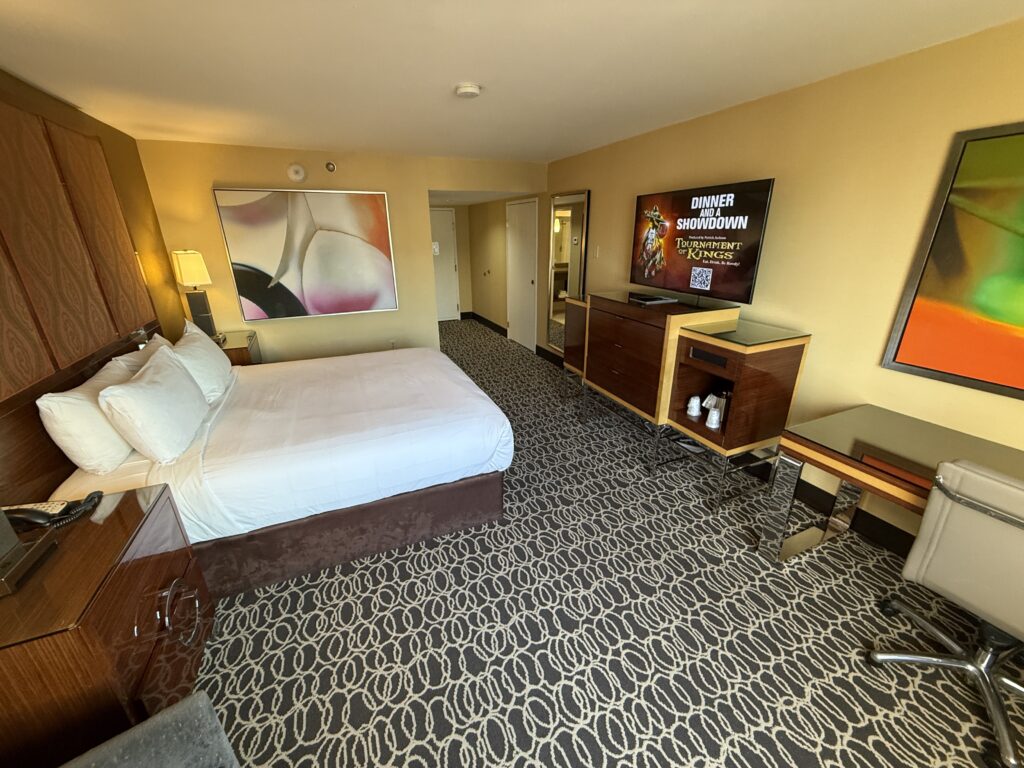 A wide angle view of the king bed pointed at the 55" TV. A workdesk is visible to the right. 