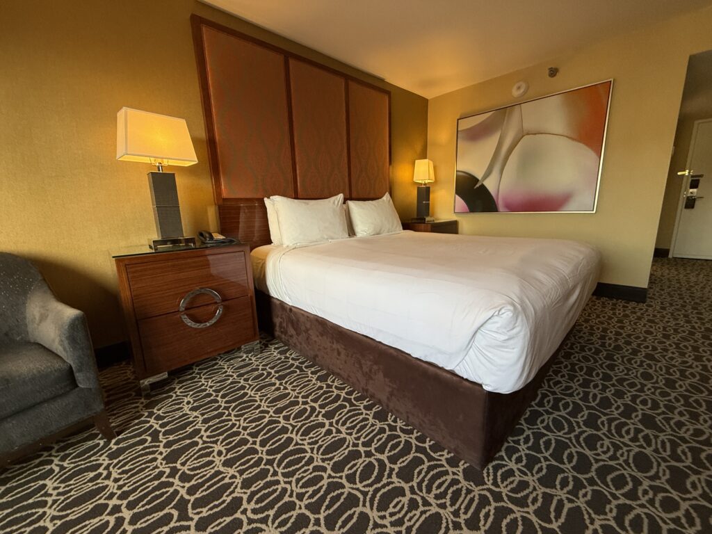A close shot of the bed, flanked by end tables with lamps turned on. 