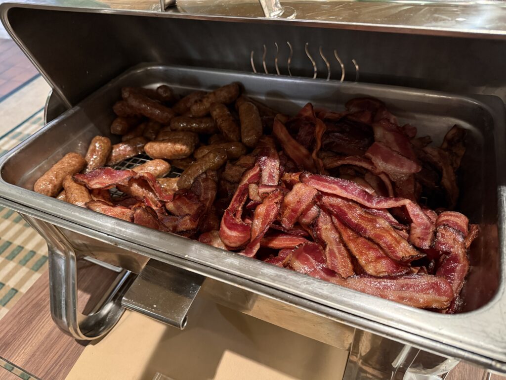 A warming tray stocked with sausage links and bacon. 