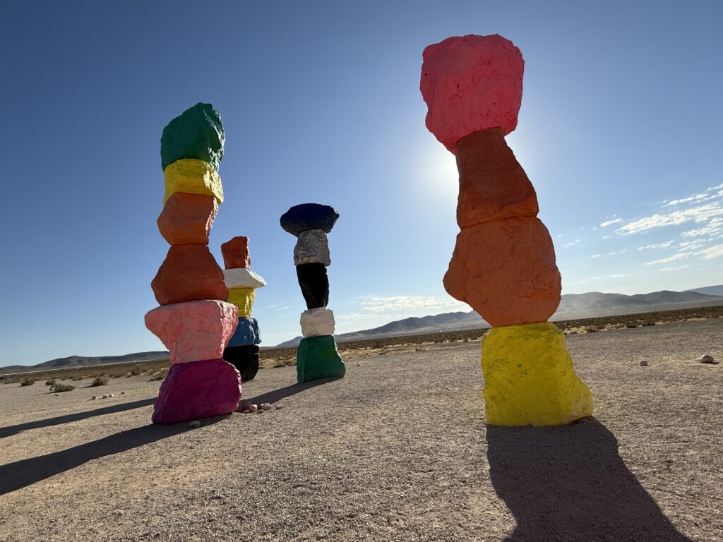 4 stacks of rocks, one of which is blocking the sun, which creates a cool glow around the totem.