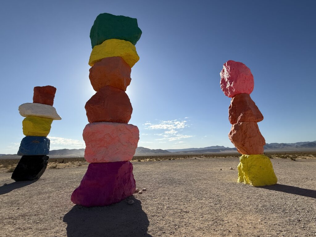 3 stacks of colorful rocks, the closest of which is blocking the sun.