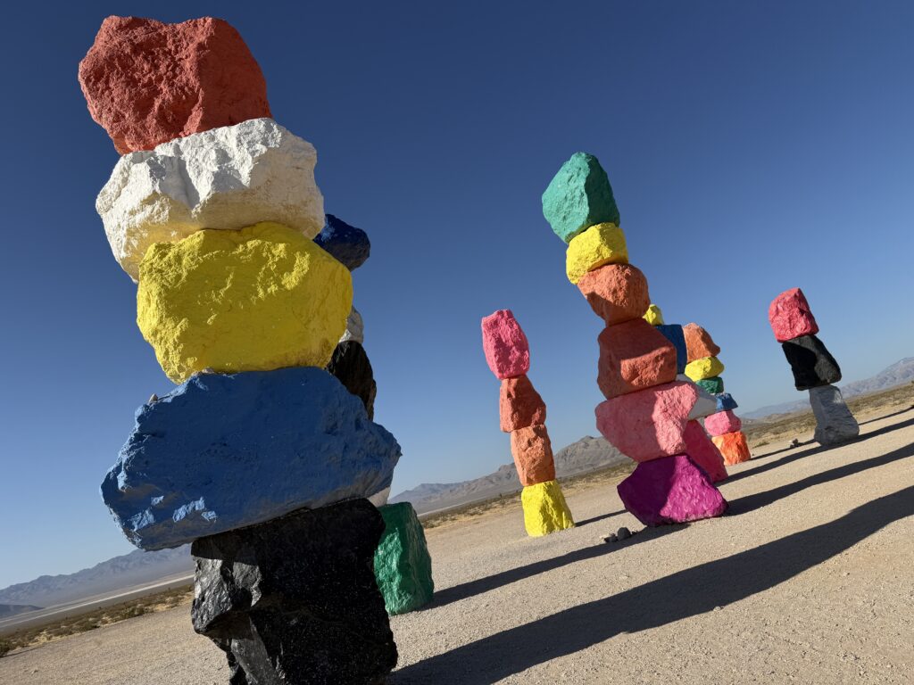 Colorful stacks of rocks in the desert with a mountain range visible in the background.