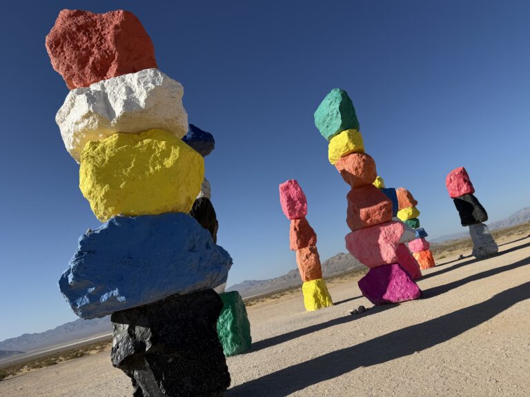 Colorful stacks of rocks in the desert with a mountain range visible in the background.