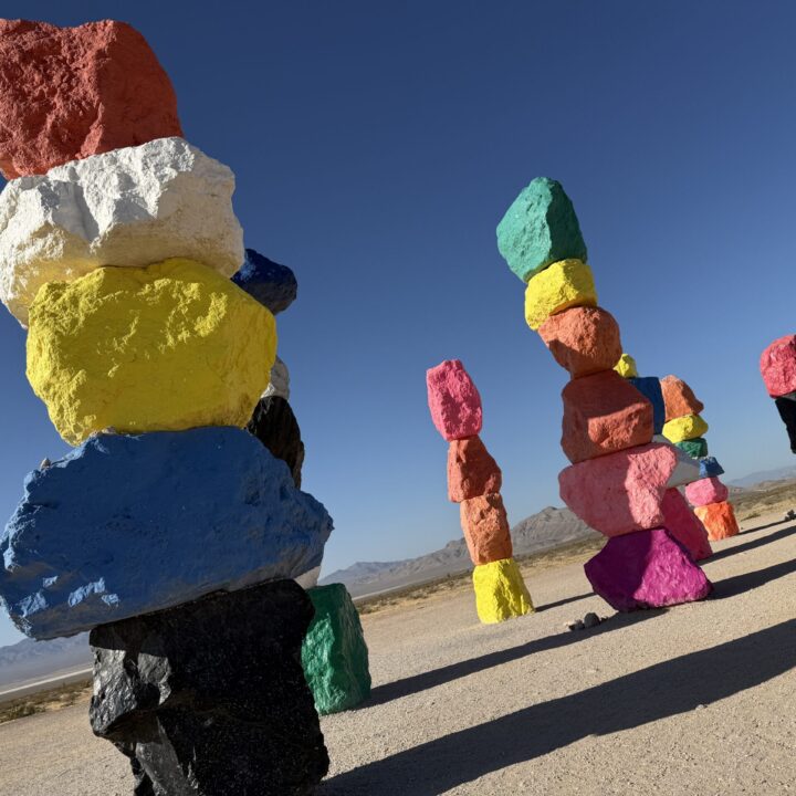 Colorful stacks of rocks in the desert with a mountain range visible in the background.