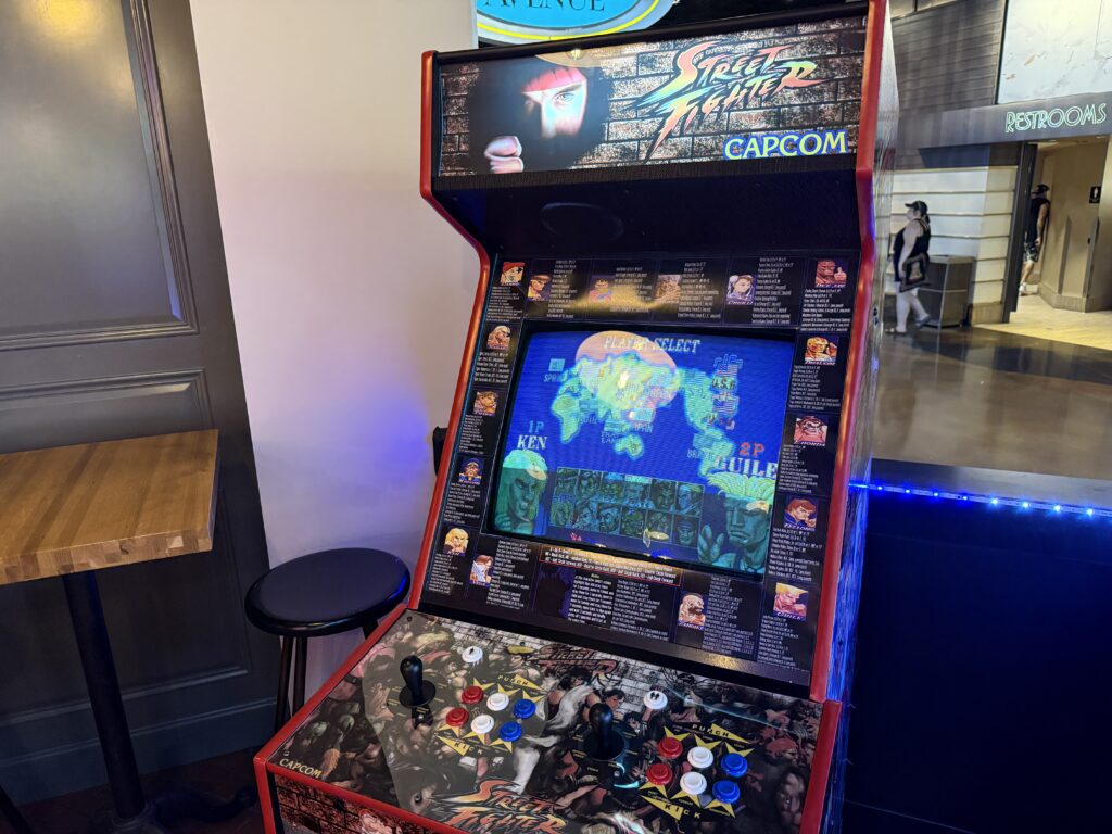 Street Fighter II arcade cabinet with colorful buttons and joystick in a dim arcade area.
