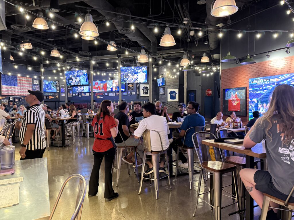 Inside TAP Sports Bar, which has a ton of customers and wall mounted TVs. 