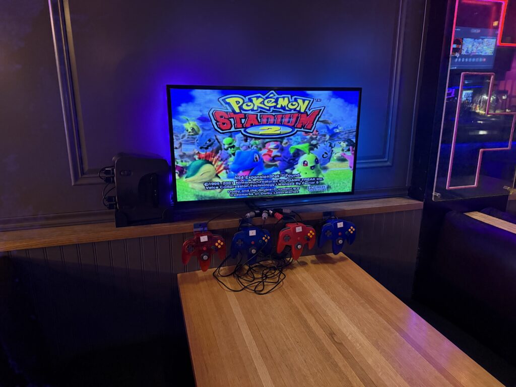 A restaurant booth with a TV mounted on the wall equipped wiith an N64.