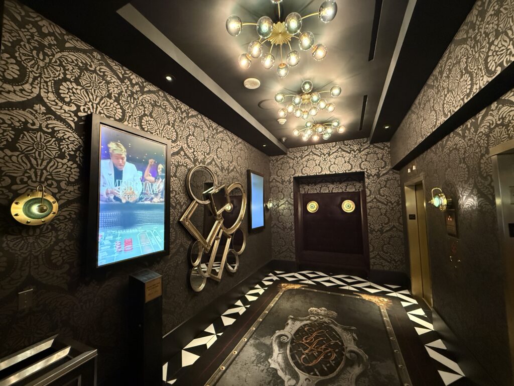 A hotel elevator lobby, which has a bench and unique mirror art on the wall. 