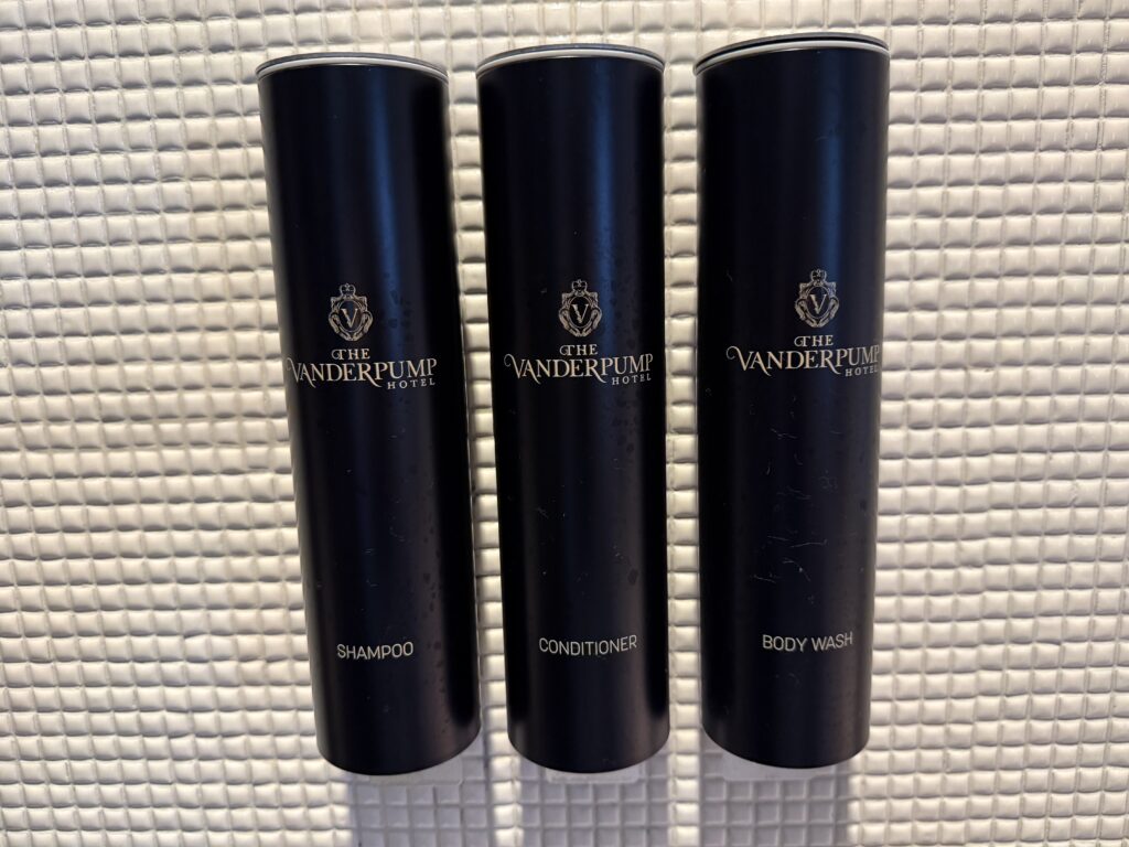 Vanderpump-brnaded bath products hanging on the wall in the shower. 