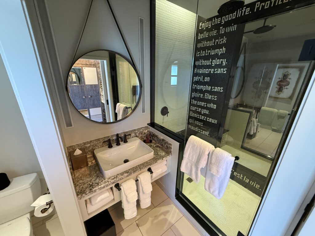 A single sink vanity with the shower in the background. 